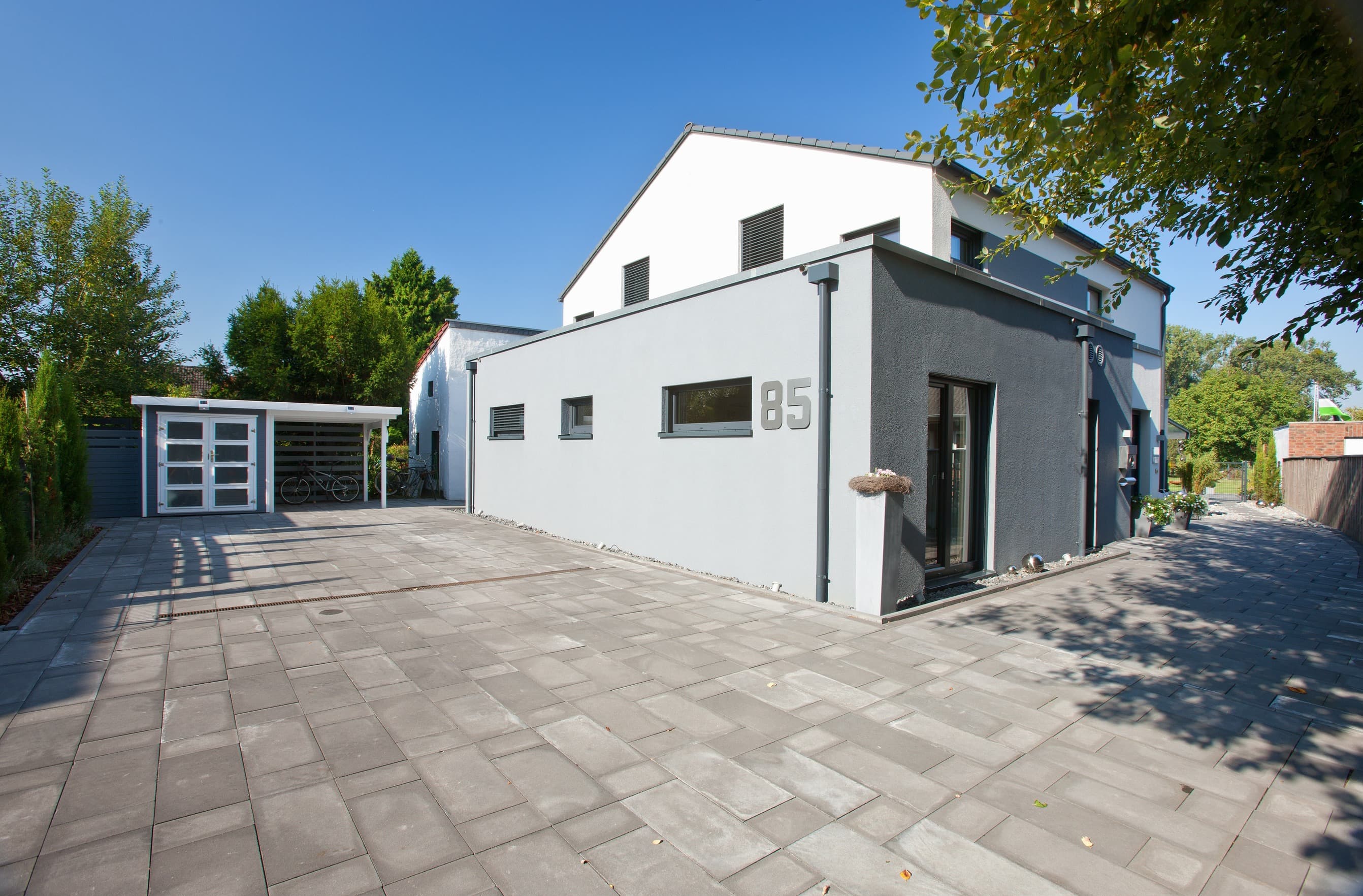 Modernes Einfamilienhaus mit Carport und gepflasterter Einfahrt im geförderten Neubau